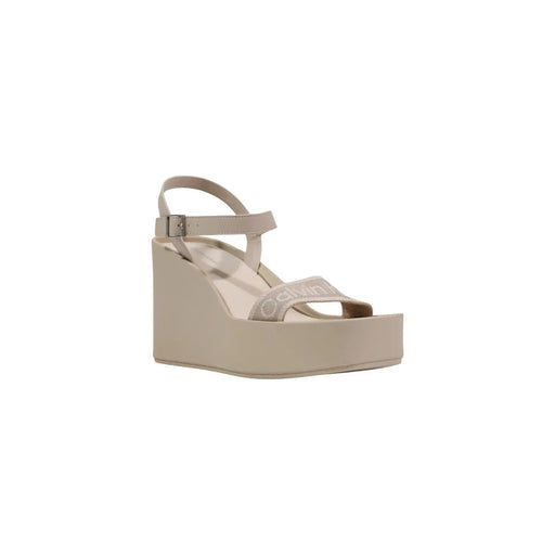 Calvin Klein Sandale compensée beige pour femme, avec une fine bride à la cheville et une bande décorative sur le pied.