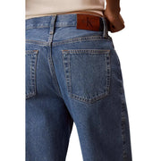 Jean Calvin Klein pour femme en denim de coton bleu, dos visible, avec un écusson de la marque en cuir marron à la taille.