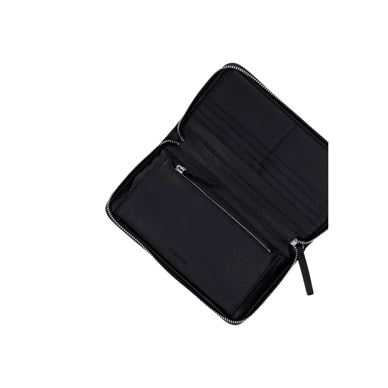 Portefeuille Calvin Klein pour femme, en polyester noir, orné d'un emblème, avec une fermeture éclair élégante et des surpiqûres discrètes.