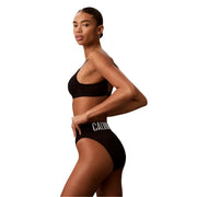 Bas de bikini noir Calvin Klein avec bande logo blanche, vu de dos, en polyester.