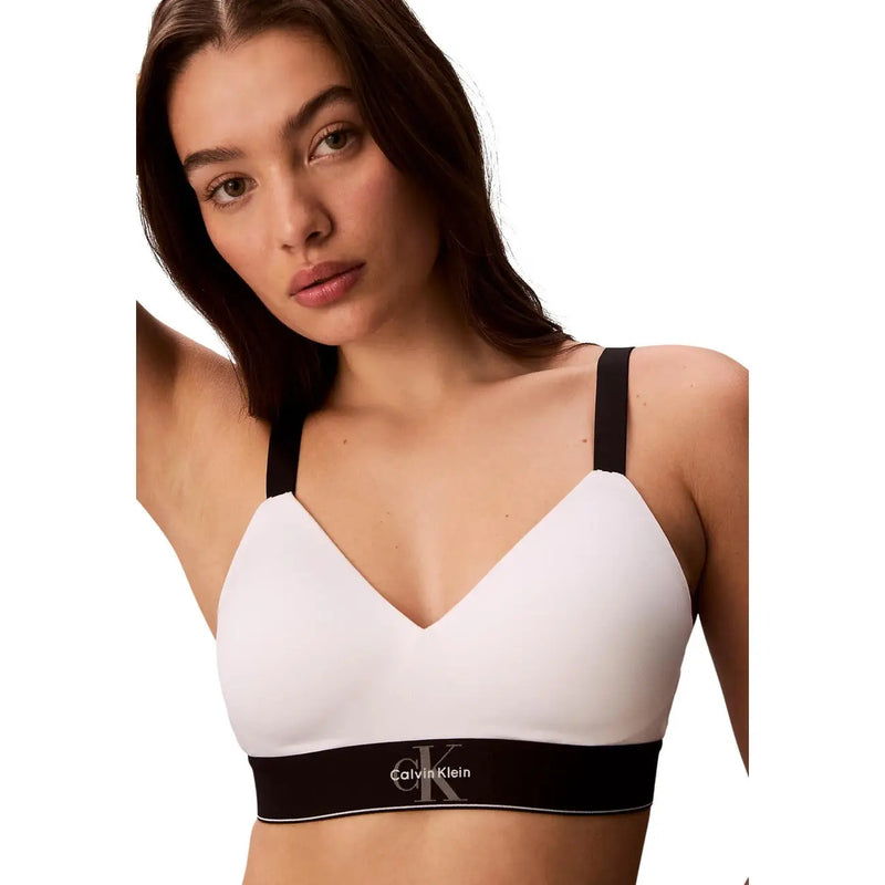 Soutien-gorge blanc Calvin Klein pour femme, légèrement doublé, avec bretelles noires et bande logo contrastante pour un confort optimal.