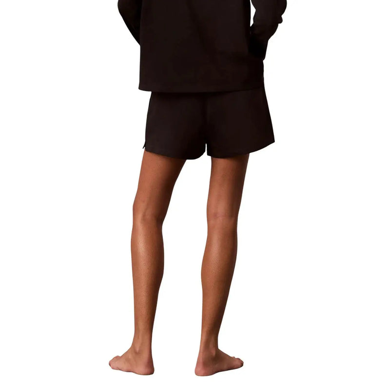 Calvin Klein Short en jersey de coton noir pour femme, avec logo, texture douce, coupe décontractée et détails de coutures latérales discrets.