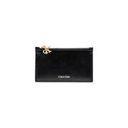 Calvin Klein Portefeuille femme en similicuir noir avec fermeture éclair, porte-cartes orné d'un charm et de surpiqûres CK dorés.