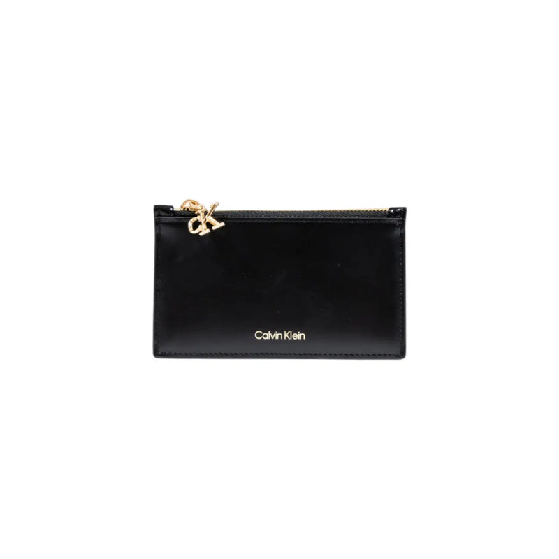 Calvin Klein Portefeuille femme en similicuir noir avec fermeture éclair, porte-cartes orné d'un charm et de surpiqûres CK dorés.