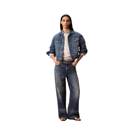 Une femme portant une veste en jean brut à manches retroussées, un jean large et un sweat-shirt blanc en coton Calvin Klein