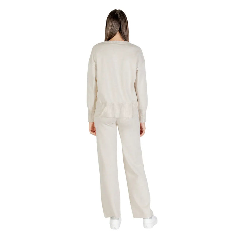Pull en maille couleur crème à poignets et ourlet côtelés, assorti à un pantalon large beige.