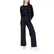 Gilet en maille noire à boutons blancs et poches avant, porté avec un pantalon Choral pour femme, en viscose mélangée noire, automne-hiver