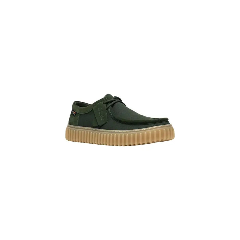 Chaussure Clarks pour homme, modèle slip-on en toile vert foncé avec semelle en caoutchouc côtelé beige et lacets noirs, en tissu léger.