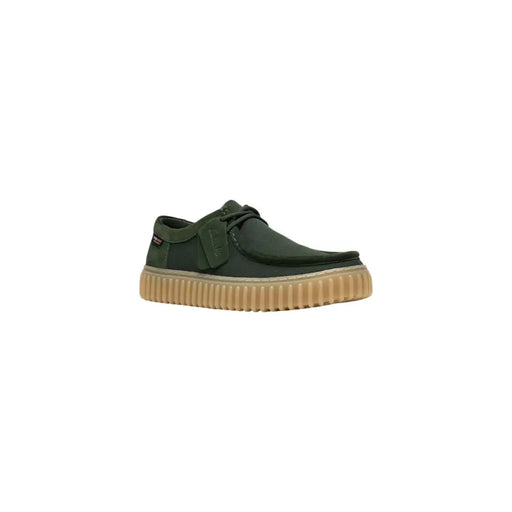 Chaussure Clarks pour homme, modèle slip-on en toile vert foncé avec semelle en caoutchouc côtelé beige et lacets noirs, en tissu léger.