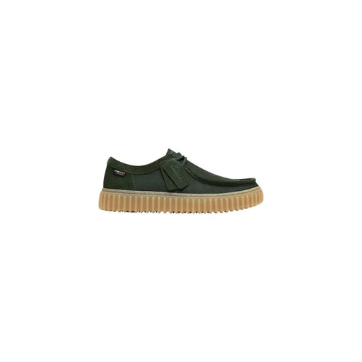 Chaussures Clarks pour homme, modèle slip-on, tige en tissu vert avec daim vert foncé, semelle en caoutchouc beige et système de laçage distinctif.