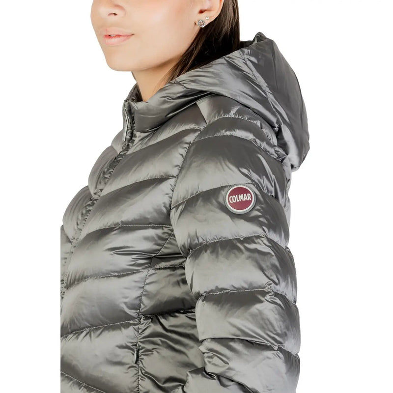Une élégante veste matelassée à capuche en polyester gris foncé, avec une finition en nylon brillant et un écusson Colmar circulaire sur la manche.