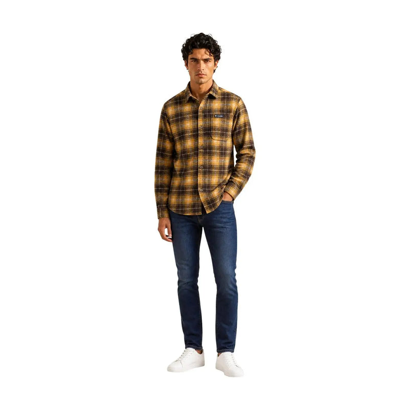 Un homme portant un Columbia Veste chemise homme marron à carreaux en polyester avec petit logo sur la poitrine et jean bleu foncé