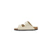 Cream-colored two-strap sandal with gold buckles displayed in a product image