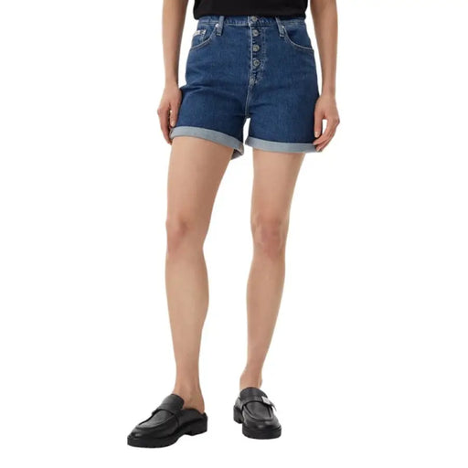 Woman wearing black T-shirt and denim button-fly shorts, stylish casual outfit