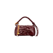 A glossy burgundy Desigual women bag featuring a braided handle, bow front closure, tassel details, and inside pocket