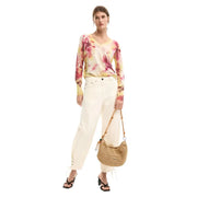 A woven straw handbag with a curved crescent shape and natural tan color featured with desigual pink floral knitwear for women
