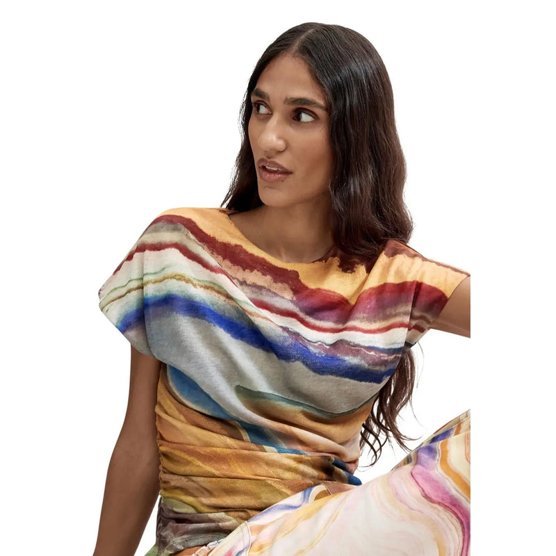 A woman wears a Desigual women beige round neck polyester t shirt with vibrant abstract stripes in earthy and bold tones