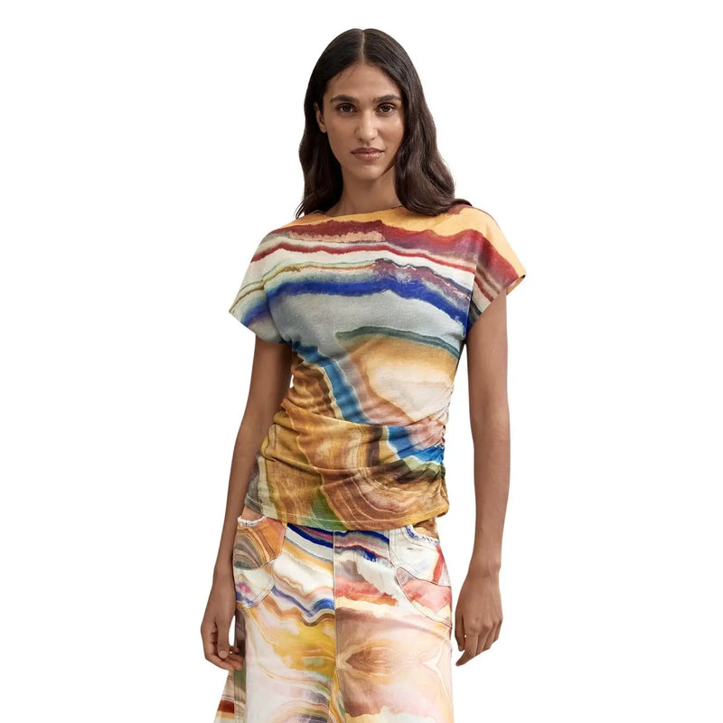 A woman wearing a Desigual women beige round neck polyester t shirt with vibrant multicolored abstract stone pattern