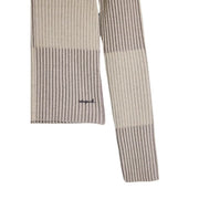 Écharpe en maille côtelée à rayures beiges et grises avec logo brodé discret, portée avec un pull à col roulé beige Desigual pour femme