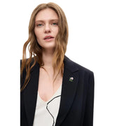 A delicate floral metallic pin with white flower and green stem on a desigual women black blazer viscose blend long lapel
