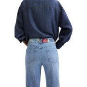 Jean Desigual en denim de coton bleu pour femme, porté avec une ceinture à motifs colorés ornée d'une boucle brodée en forme de rose.