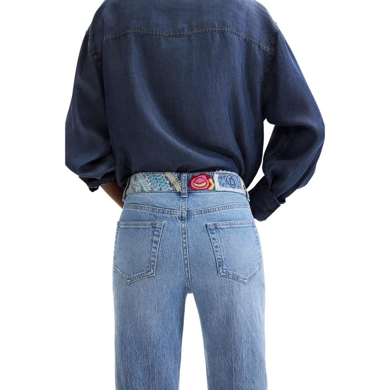 Jean Desigual en denim de coton bleu pour femme, porté avec une ceinture à motifs colorés ornée d'une boucle brodée en forme de rose.