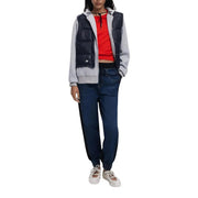 Doudoune sans manches matelassée bleu marine à manches grises et fermeture éclair sur le devant, portée avec un jean en denim de coton stretch bleu marine Desigual pour femme.