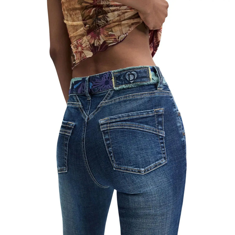 Jean Desigual pour femme en denim bleu stretch de coton, orné d'un passant de ceinture fleuri et d'un logo en forme de cœur (face arrière).