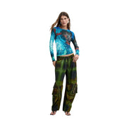 Une femme porte un pull Desigual bleu en viscose avec un imprimé de plumes bleues et noires sur le devant.