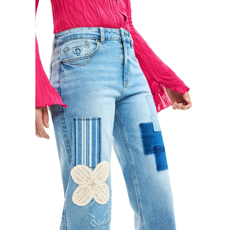 Jean Desigual pour femme en denim de coton bleu clair, orné d'un patchwork délavé, d'une croix appliquée et d'une fleur crochetée blanc cassé.