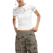 Chemise blanche à manches courtes top avec un texte noir manuscrit associé à un pantalon Desigual pour femme, gris à motifs, zippé, en viscose mélangée.