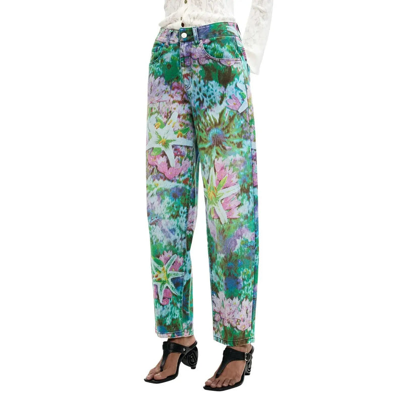 Jean Desigual pour femme en coton bleu clair à motifs floraux, avec un pantalon en denim à jambes larges orné de motifs floraux éclatants dans les tons vert, rose et violet.
