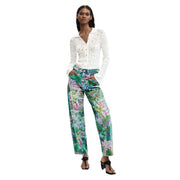 Femme portant un jean Desigual bleu clair en coton à imprimé floral vif et à jambes larges, et une chemise en dentelle blanche.