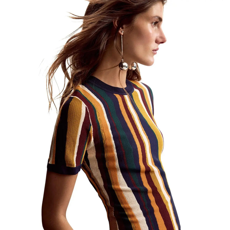 A woman wears a short-sleeved knitted dress with mustard yellow striped viscose fabric by Desigual