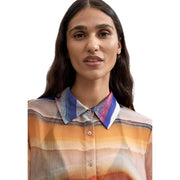 A woman wearing a desigual women orange polyester button blouse with semi sheer warm stripes and a bold striped collar