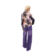 Une femme porte un pull Desigual rose à fleurs en maille de coton avec un chemisier tie-dye violet vif, noir et pêche.
