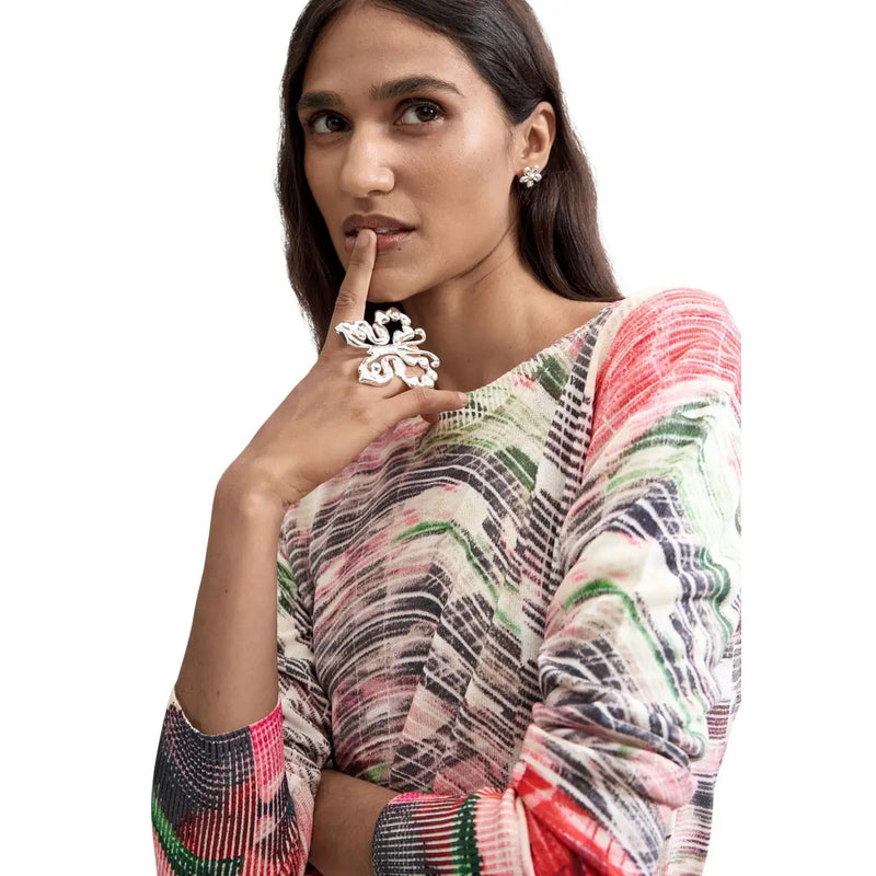 Une bague en argent finement ouvragée en forme de papillon, portée à un doigt assorti à un pull rouge en maille viscose Desigual pour femme