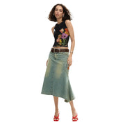 Une jupe en jean mi-cuisse bleu délavé à ourlet asymétrique et poche avant, associée à un débardeur fleuri Desigual pour femme à col rond. top noir