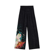 Pantalon noir à jambes larges en viscose de Desigual, orné d'un imprimé floral tropical vibrant avec des fleurs roses et des feuilles orange.