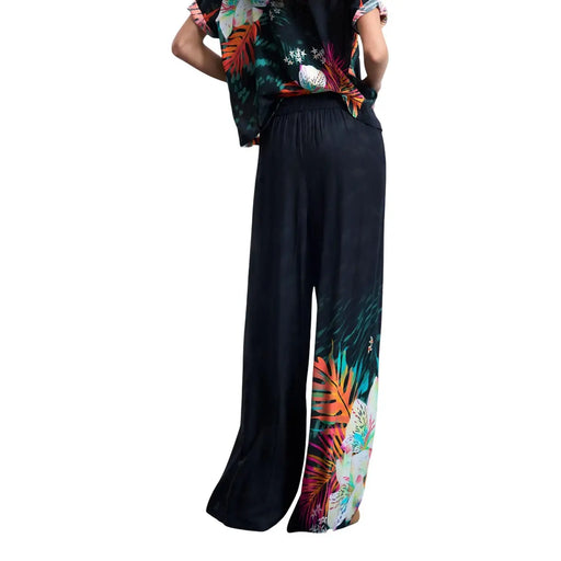 Pantalon Desigual pour femme, noir, à jambes larges en viscose, orné d'un imprimé tropical vibrant de feuilles orange, vertes et roses sur le bas des jambes.
