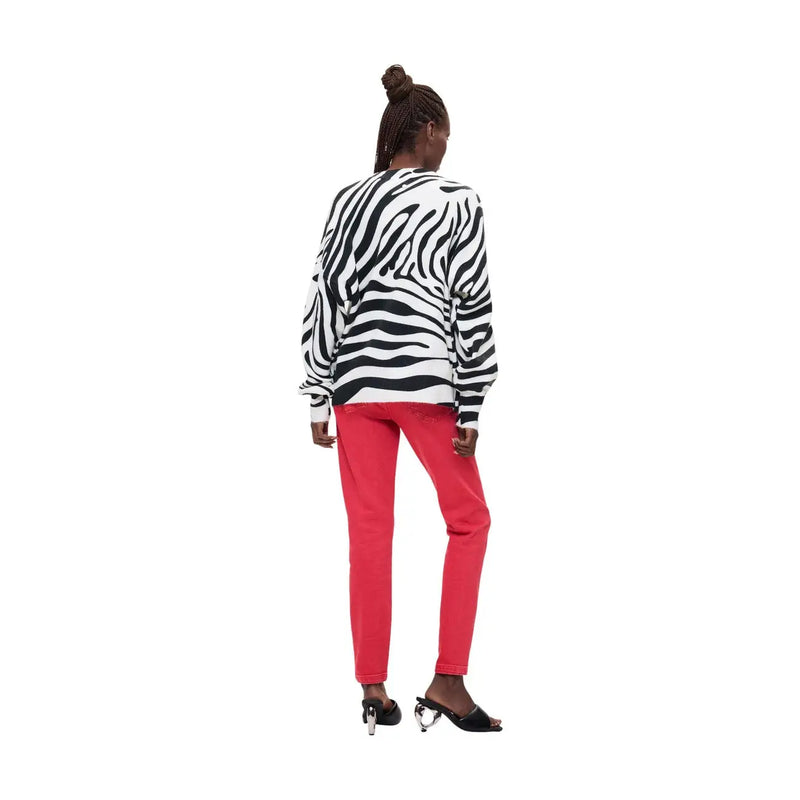 A woman wearing desigual women white knitwear regular fit acrylic blend zebra-striped long-sleeved sweater and red pants