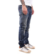 Dark blue distressed denim jeans with white sneakers and tattoos.