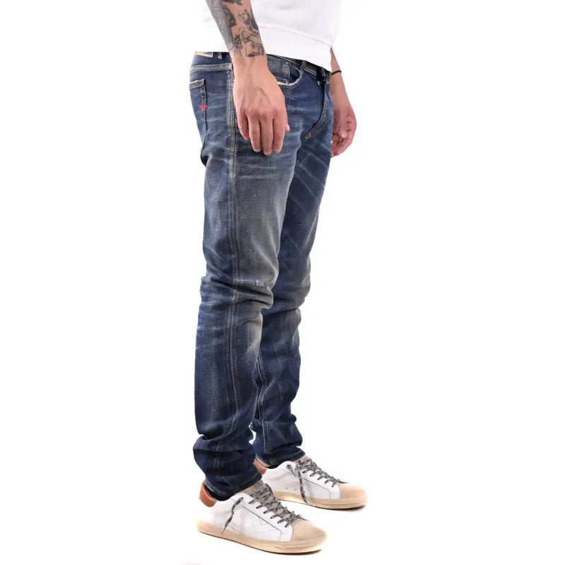 Dark blue distressed denim jeans with white sneakers and tattoos.