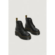 Bottines Dr Martens en cuir noir pour femme, dévoilant l'arrière avec la bride emblématique au talon.