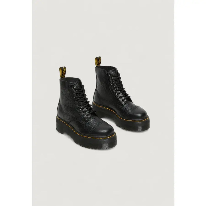 Bottines Dr Martens en cuir noir pour femme, dévoilant l'arrière avec la bride emblématique au talon.