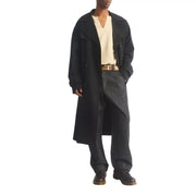 Trench-coat noir croisé à col classique et poignets boutonnés, porté avec des bottines Dr. Martens Ambassador en cuir marron pour homme.