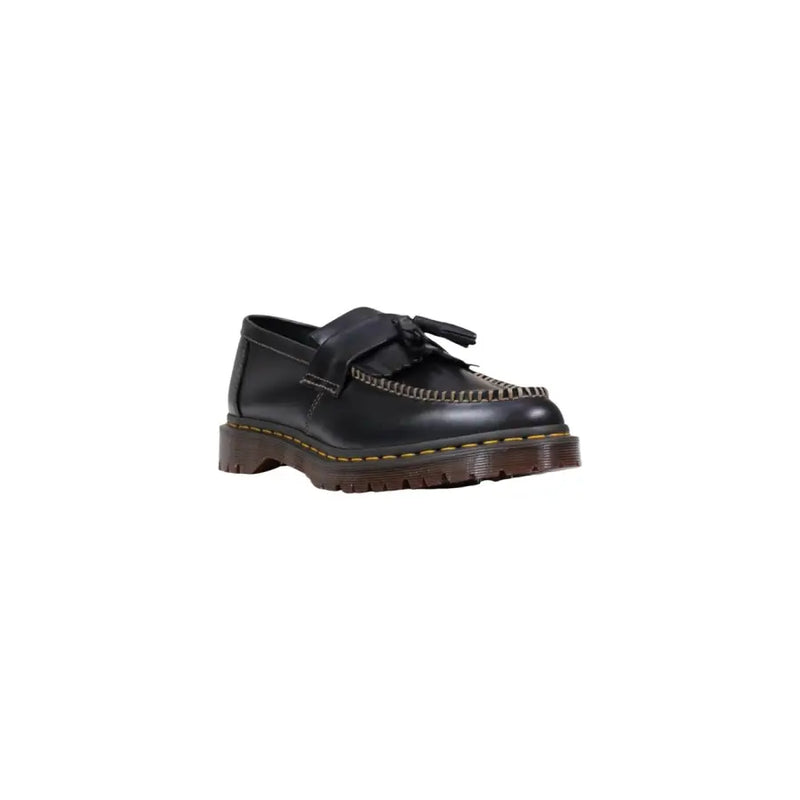 Mocassin Dr Martens pour homme en cuir noir, à enfiler, avec pompons, surpiqûres jaunes et semelle épaisse marron.