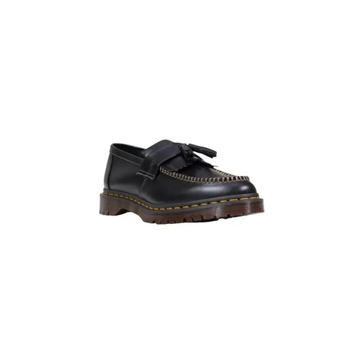 Mocassin Dr Martens pour homme en cuir noir, à enfiler, avec pompons, surpiqûres jaunes et semelle épaisse marron.
