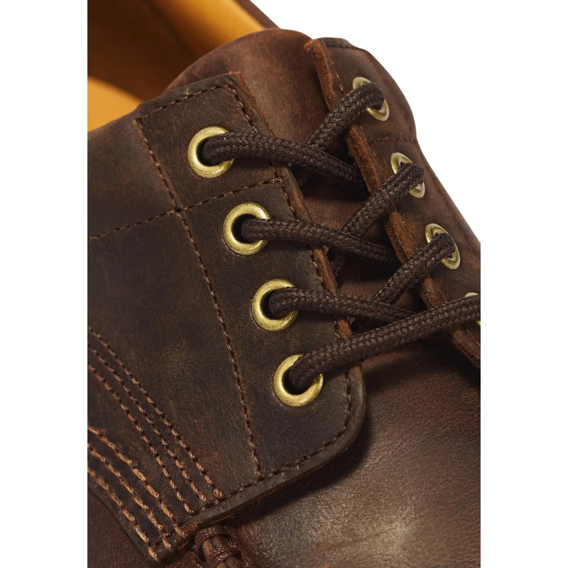 Bottes Dr. Martens pour homme, en cuir marron, à lacets, avec œillets couleur laiton.
