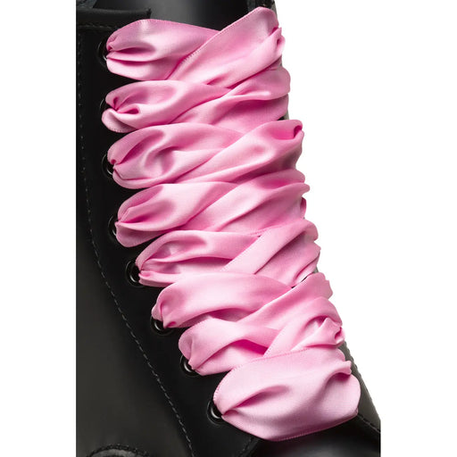 Bottes Dr. Martens pour femmes, en tissu rose, avec lacets en satin rose passant dans des œillets noirs.